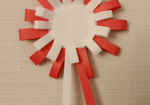 Kotylion wykonany z papieru, czyli koliste rozetki składające się z dwóch okręgów białego centralnego i czerwonego okalającego